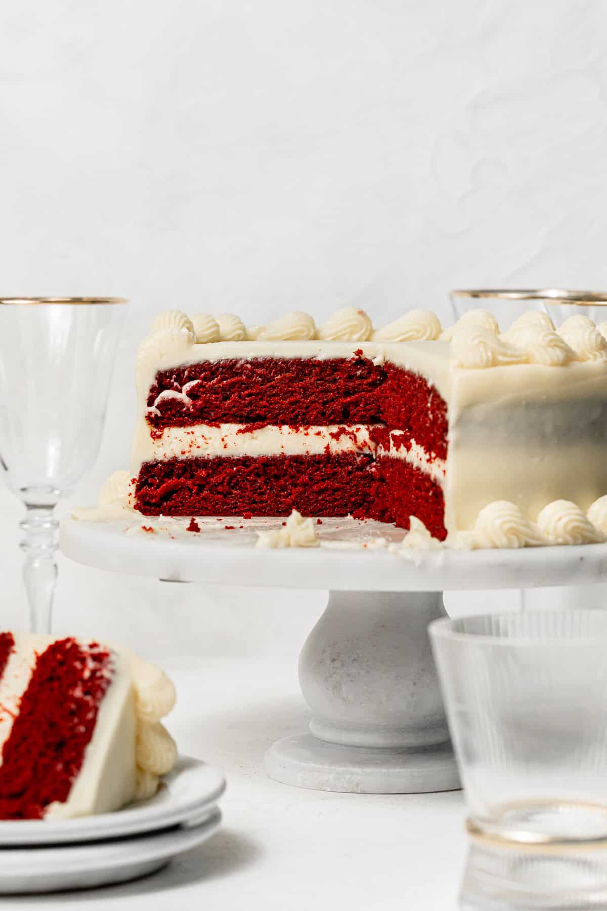 red velvet layer cake on cake stand cut to show inside. 