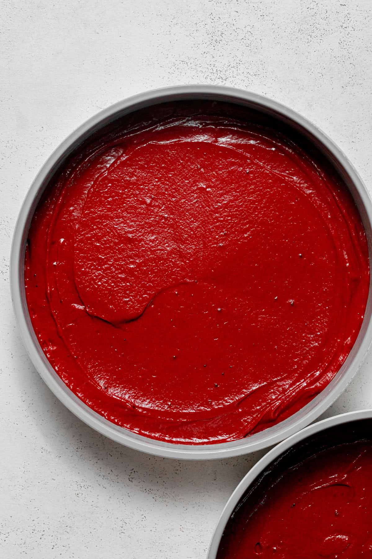 red velvet cake batter in cake pans.