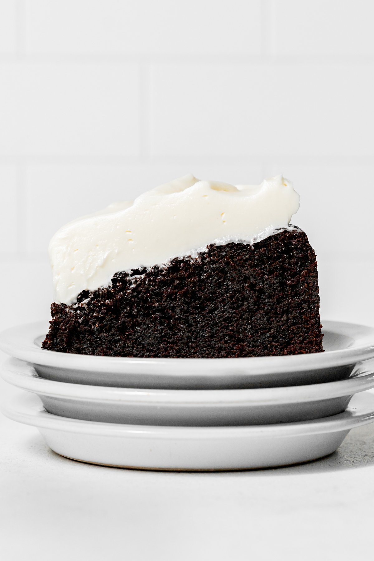 slice of chocolate Guinness cake on stack of white plates.