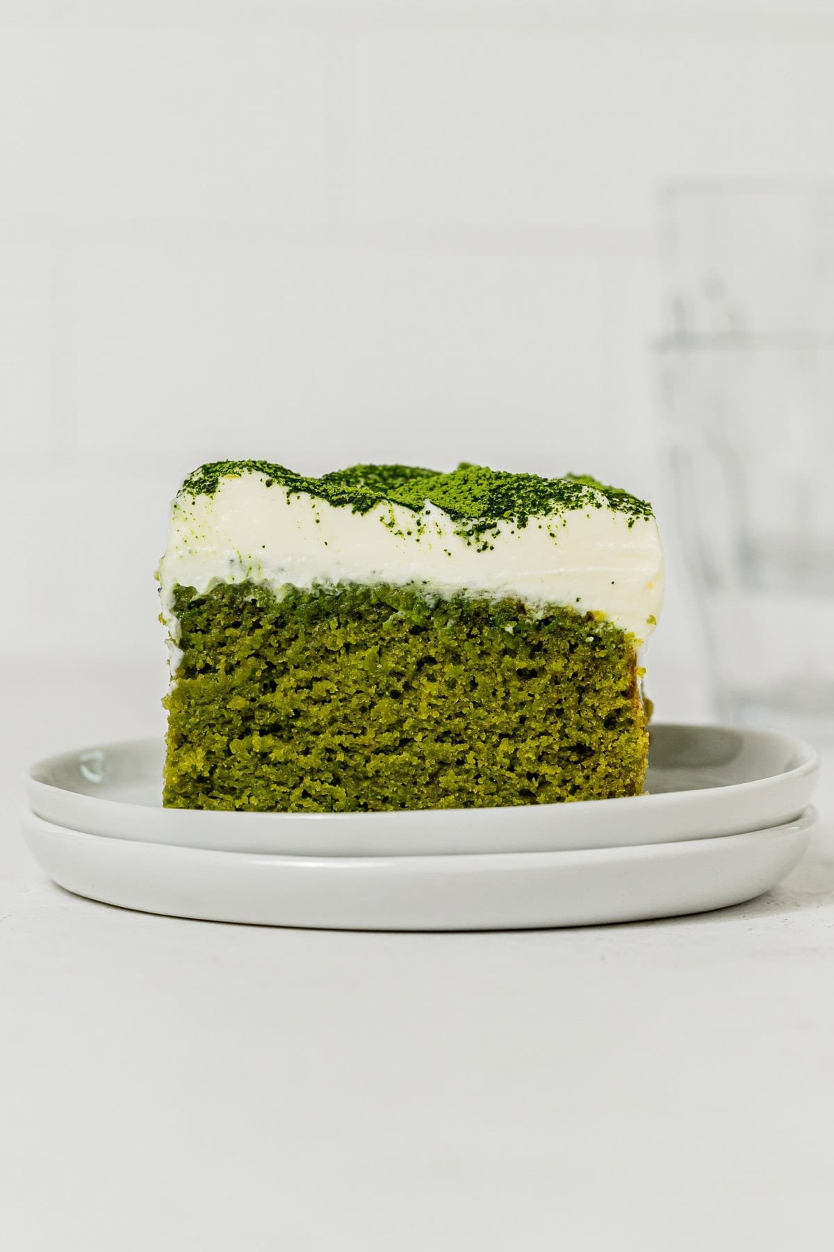Slice of matcha cake on stacked white plates.
