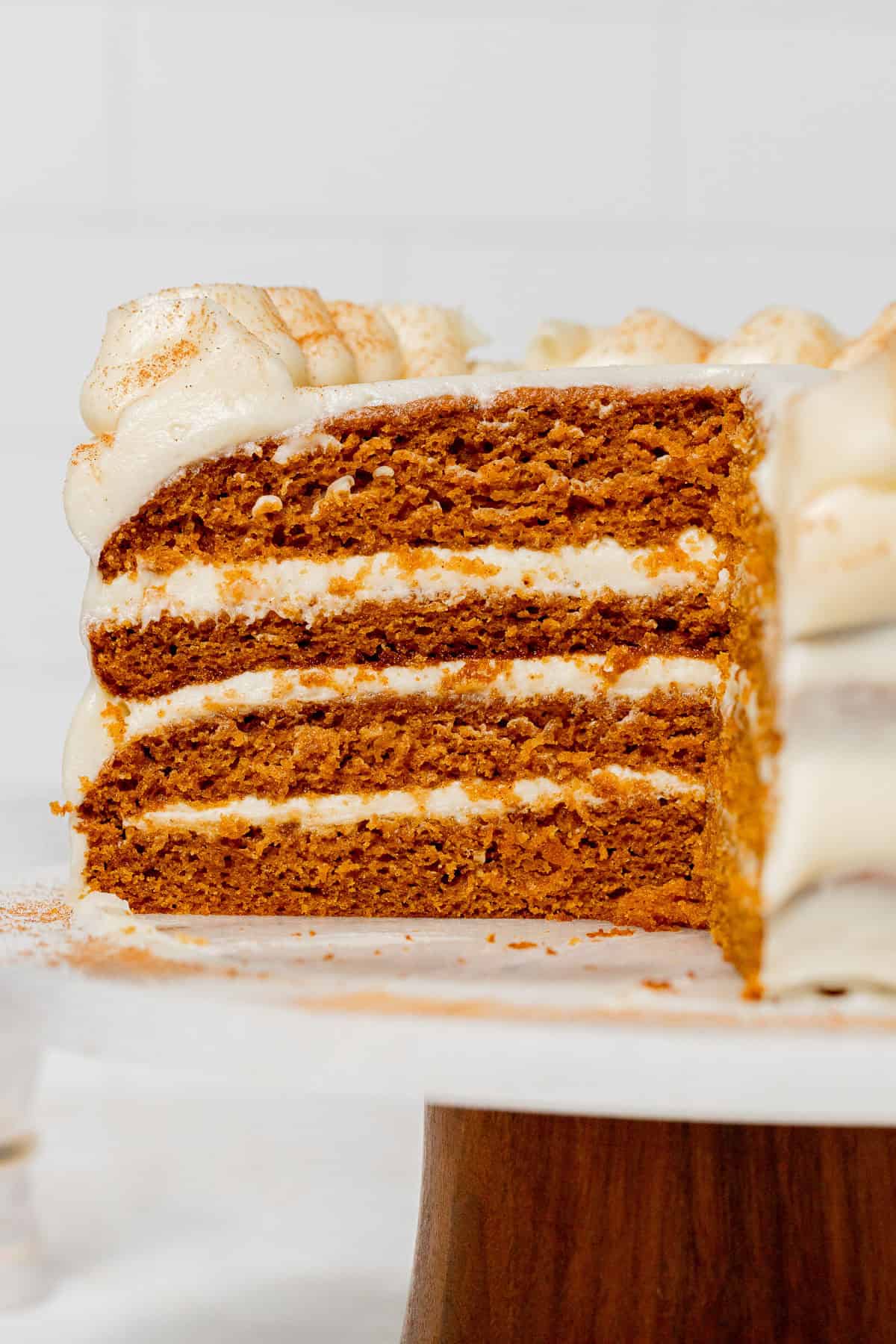 Pumpkin Cake with Cream Cheese Frosting on cake stand cut to show cross section.