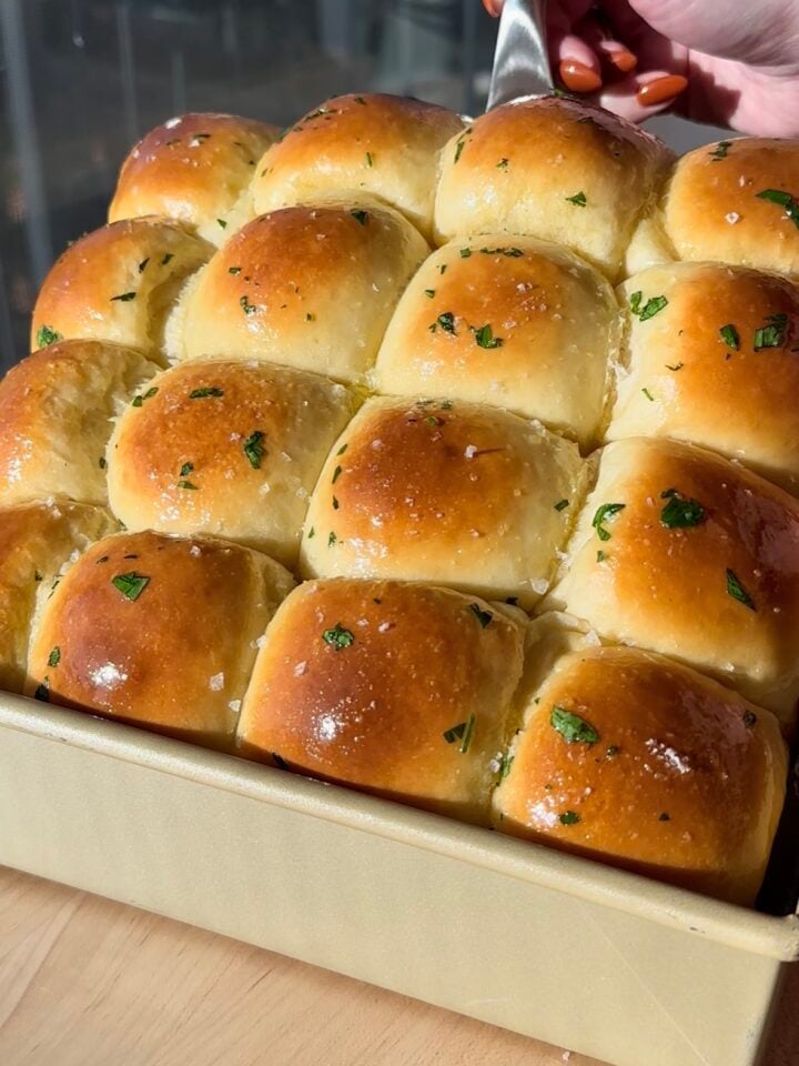 Garlic Herb Milk Bread Dinner Rolls lifted up out of pan.