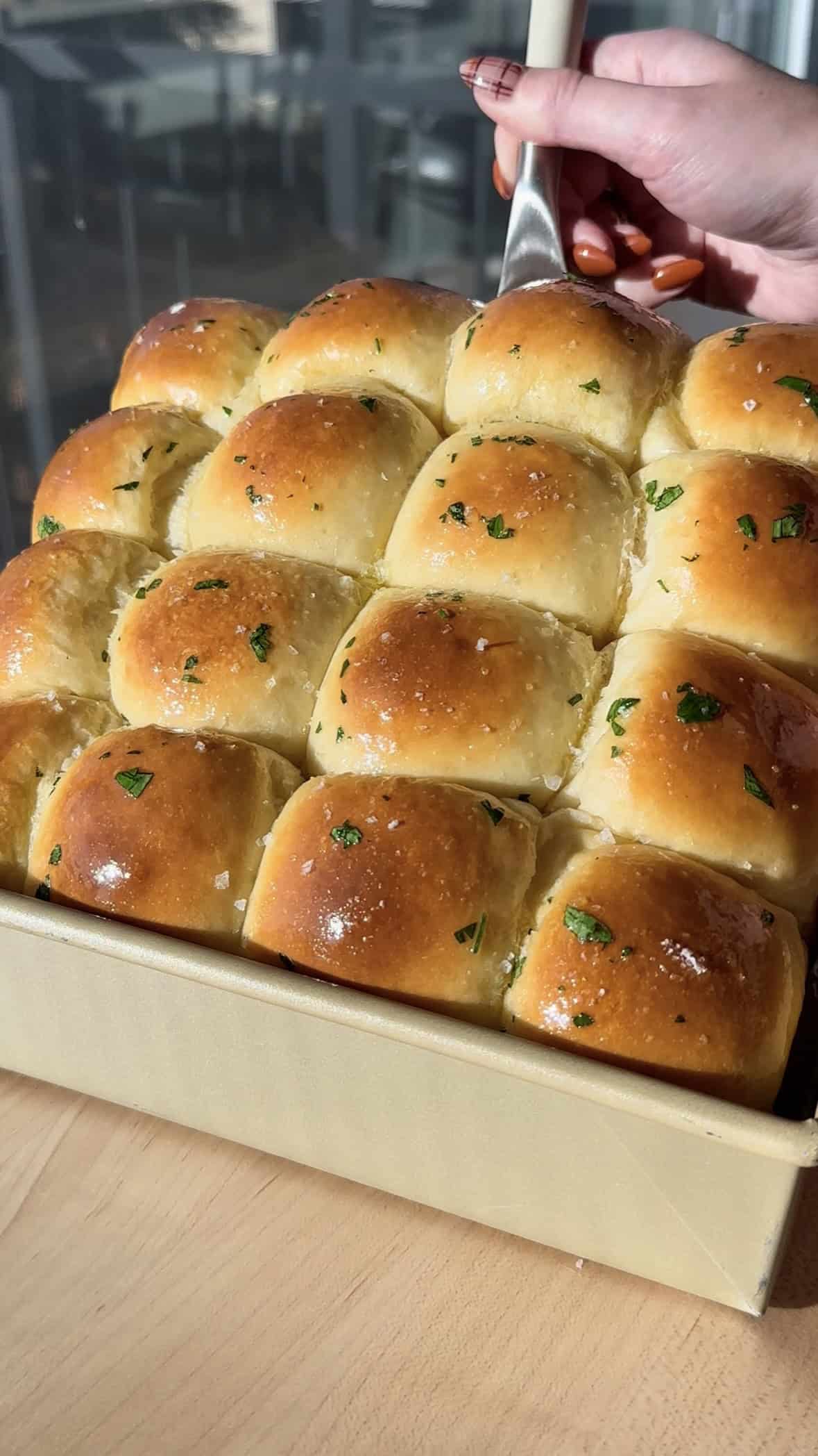 Garlic Herb Milk Bread Dinner Rolls lifted up out of pan.