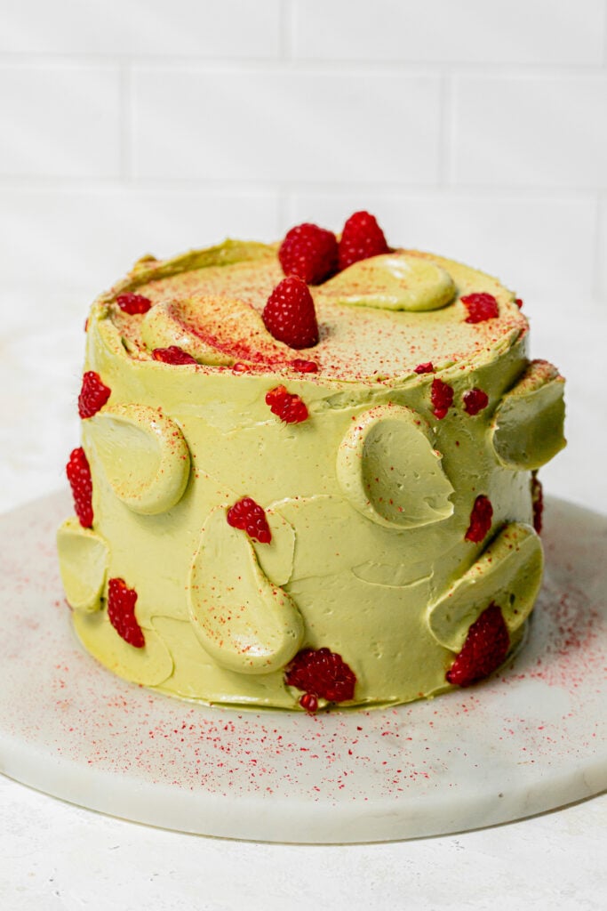 Pistachio Raspberry Cake decorated with fresh raspberries.