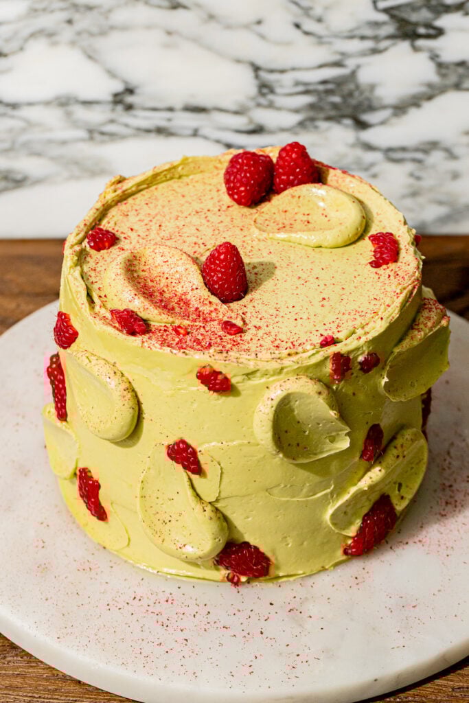 pistachio raspberry cake on marble platter.