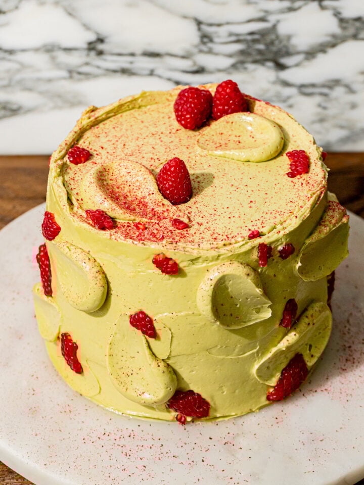 pistachio raspberry cake on marble platter.