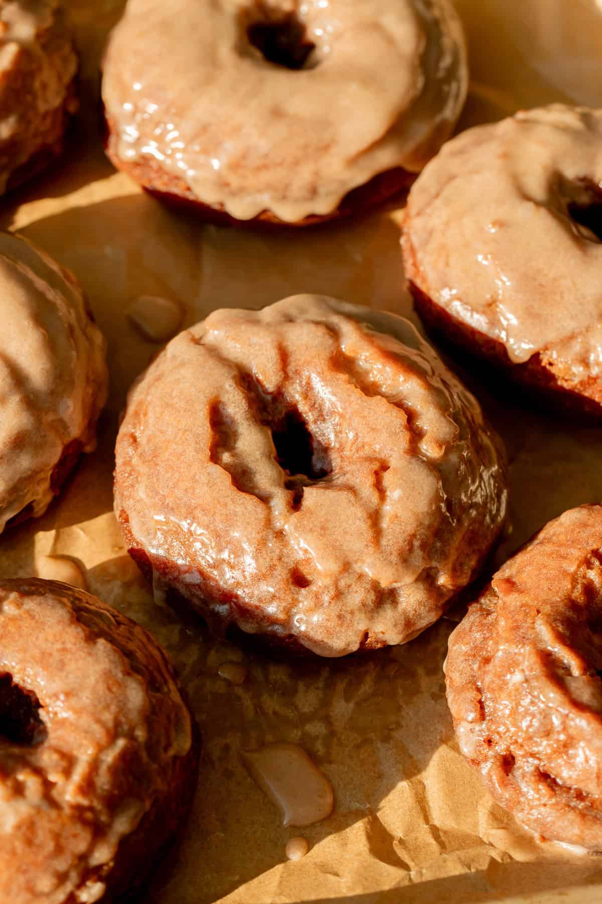 Old-Fashioned Banana Bread Donuts on parchment lined baking sheet.