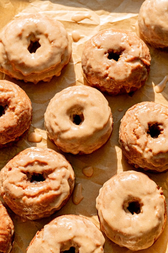Old-Fashioned Banana Bread Donuts with cinnamon glaze on parchment paper.