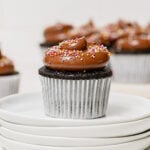 chocolate birthday cupcake on stack of white plates.