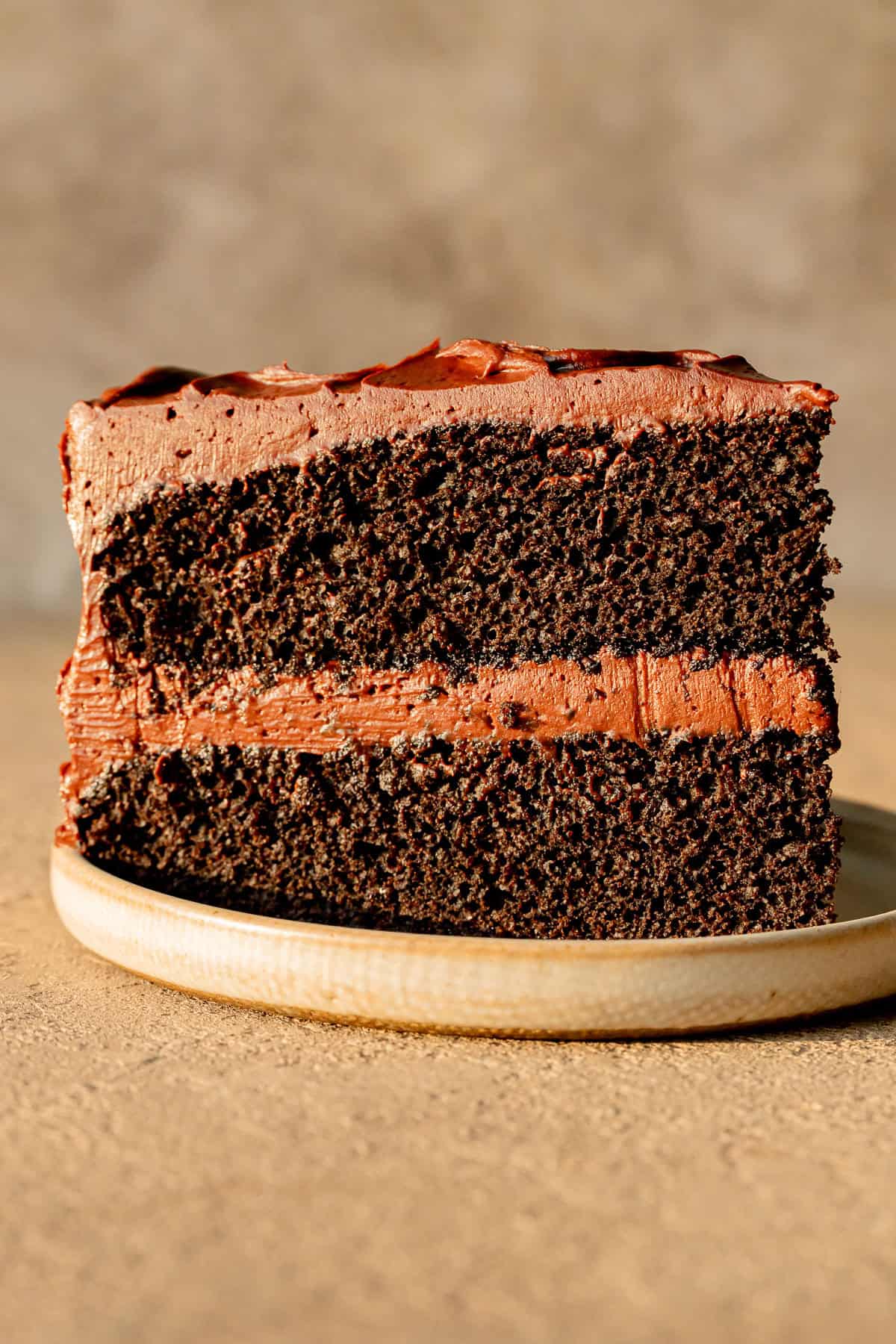 slice of chocolate ganache cake standing up on plate.