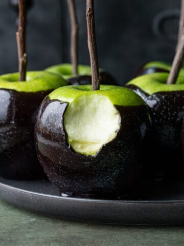 bite taken out of black poison caramel apple.