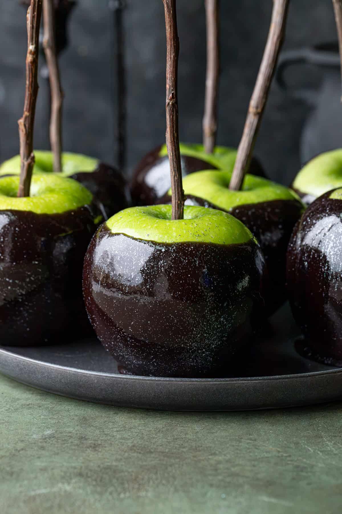 Black Poison Caramel Apples on black plate.