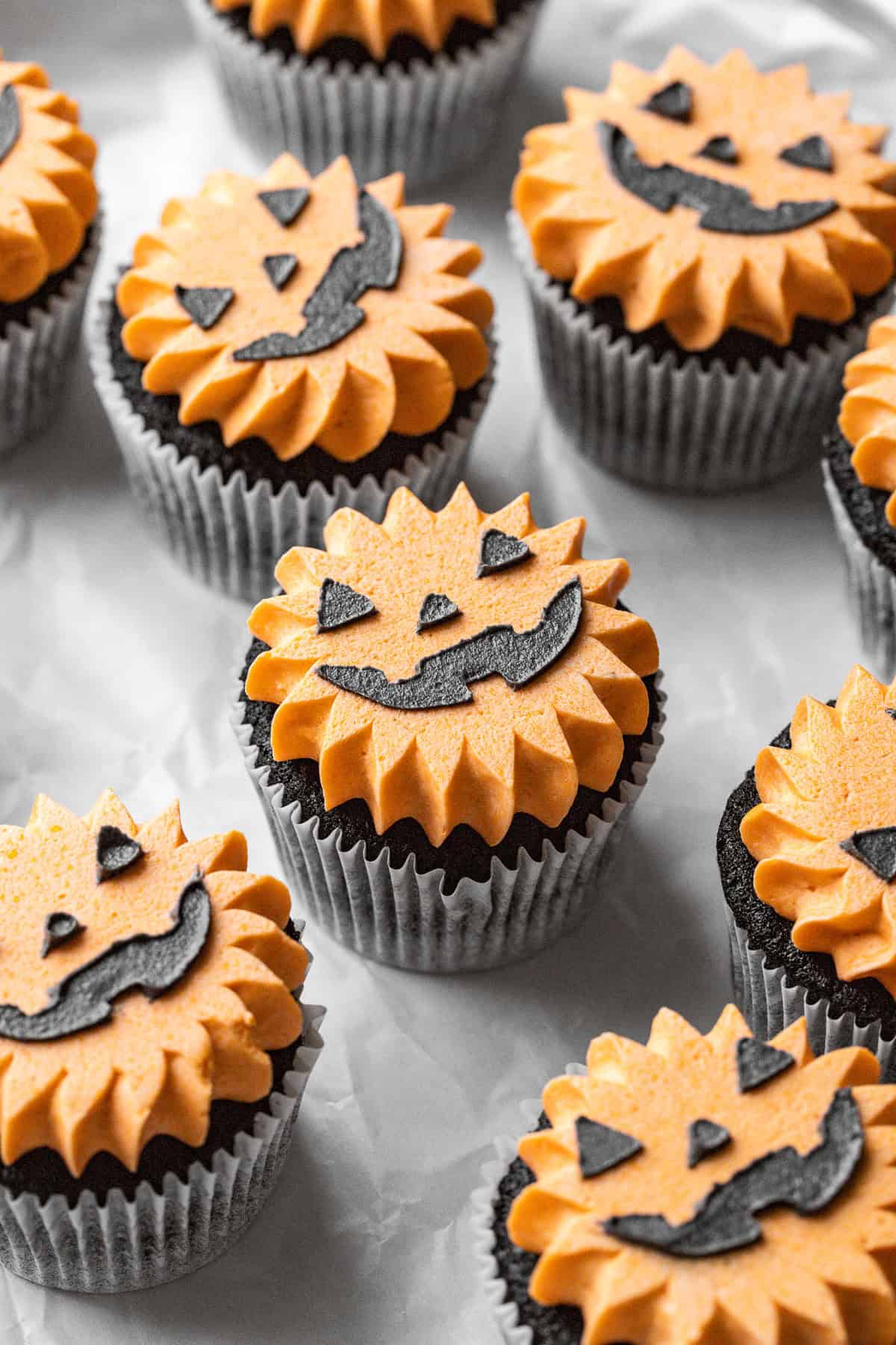 angled view of Black Velvet Jack-O’-Lantern Cupcakes on parchment.
