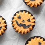 black velvet jack-o'-lantern cupcakes on parchment paper.