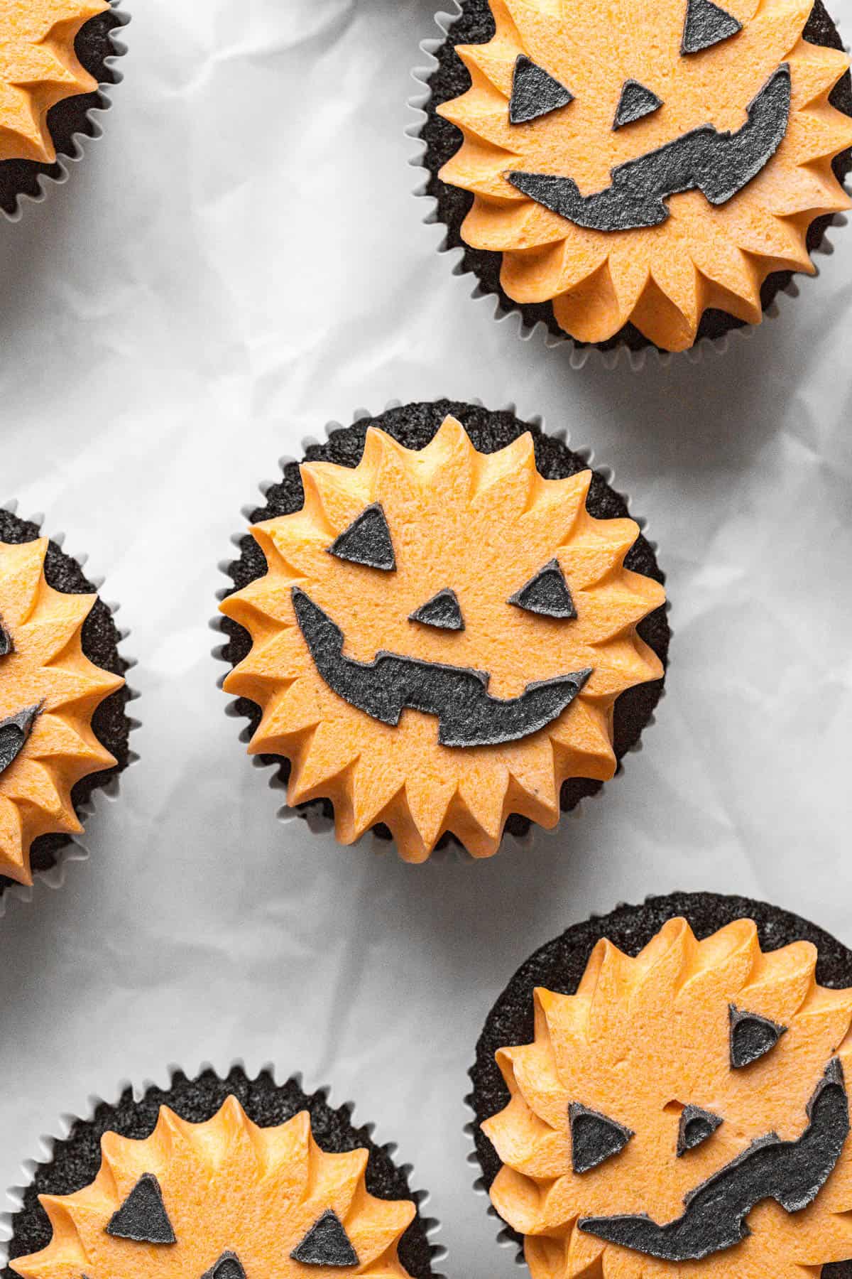 black velvet jack-o'-lantern cupcakes on parchment paper.