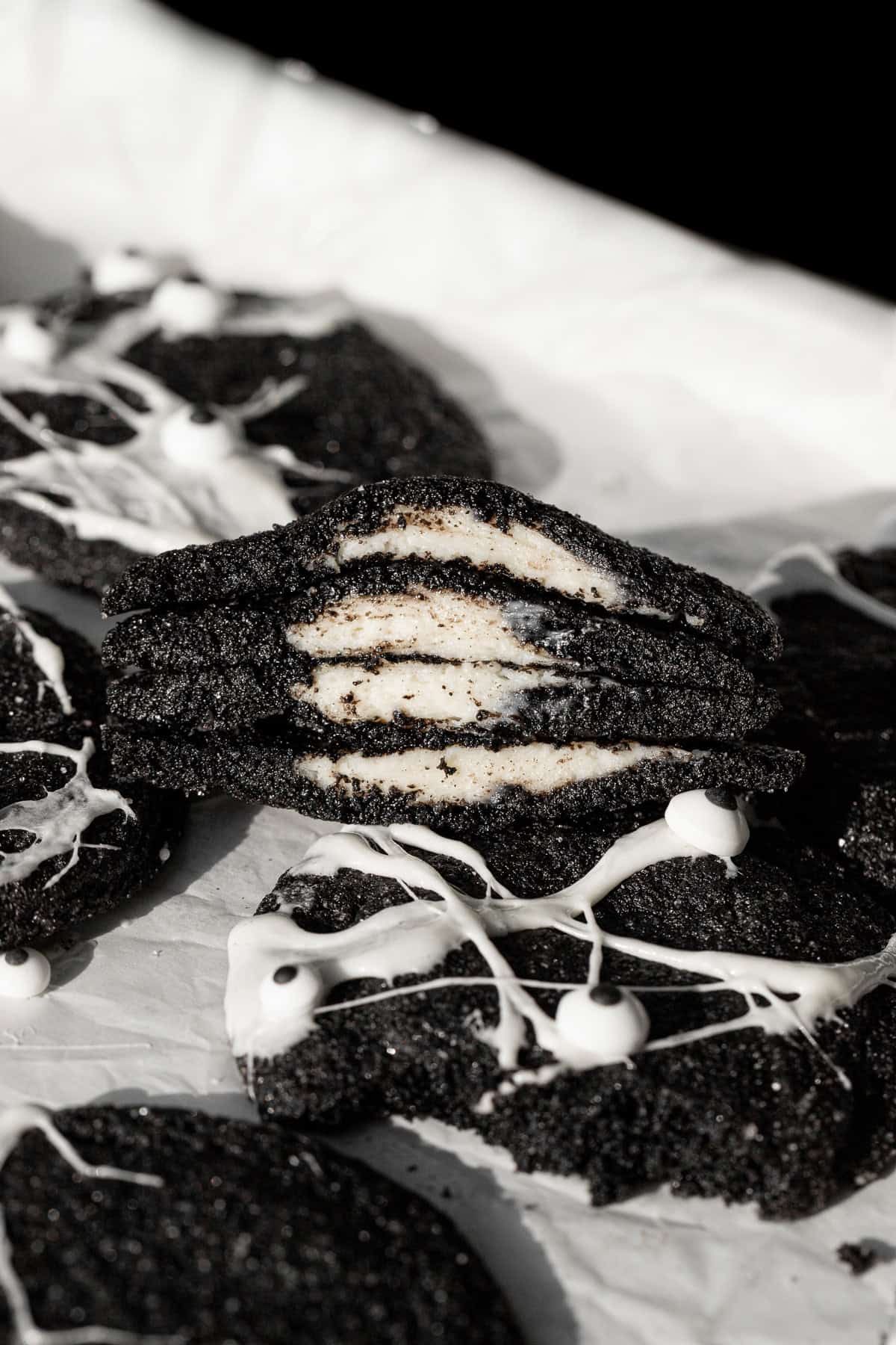 Spiderweb Black Velvet Cheesecake Cookies cut in half to reveal cheesecake filling.
