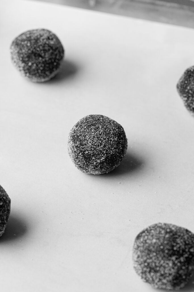 assembled cookie dough balls rolled in sugar on baking sheet.